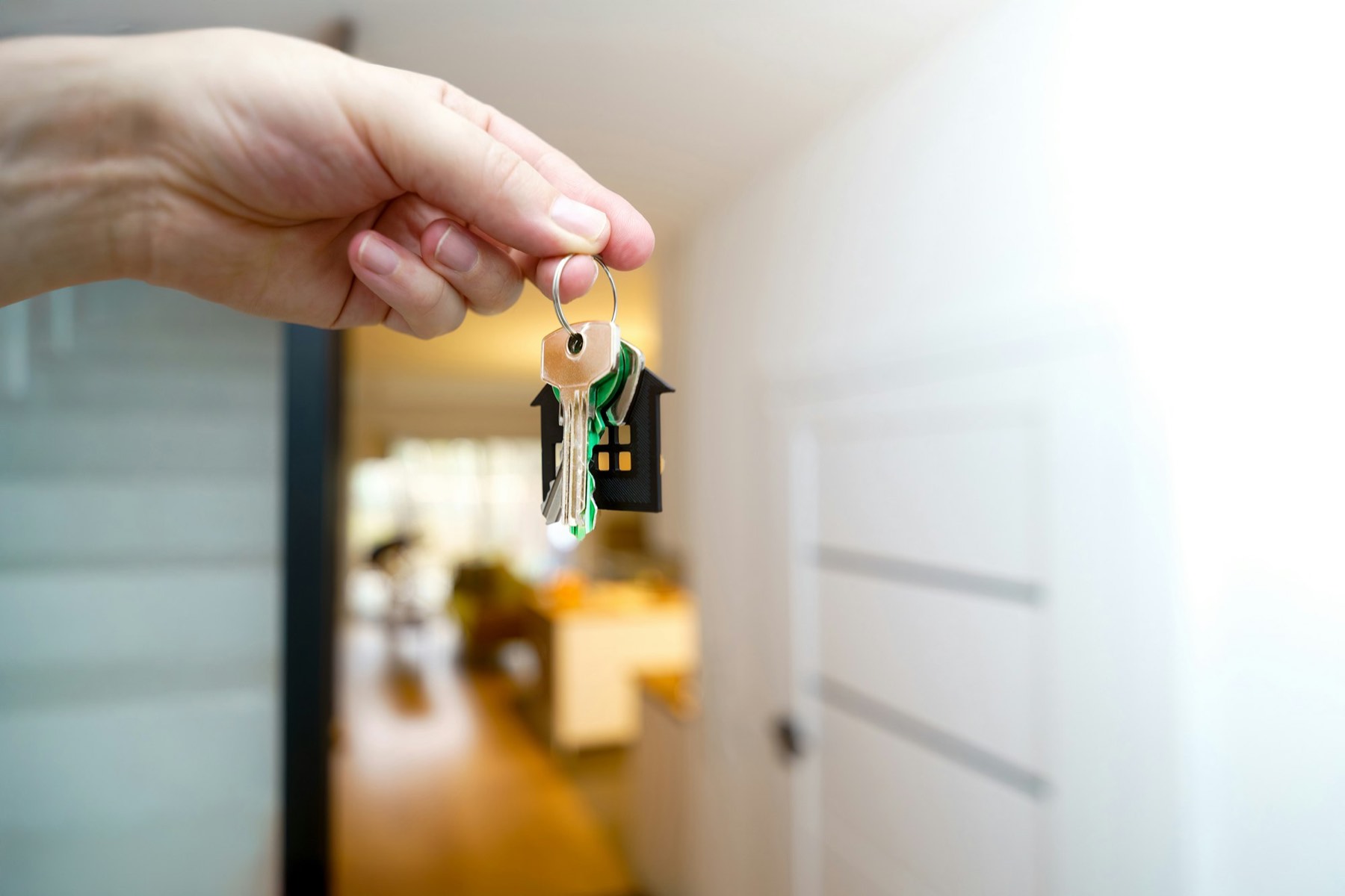 A hand holding house keys in front of a door